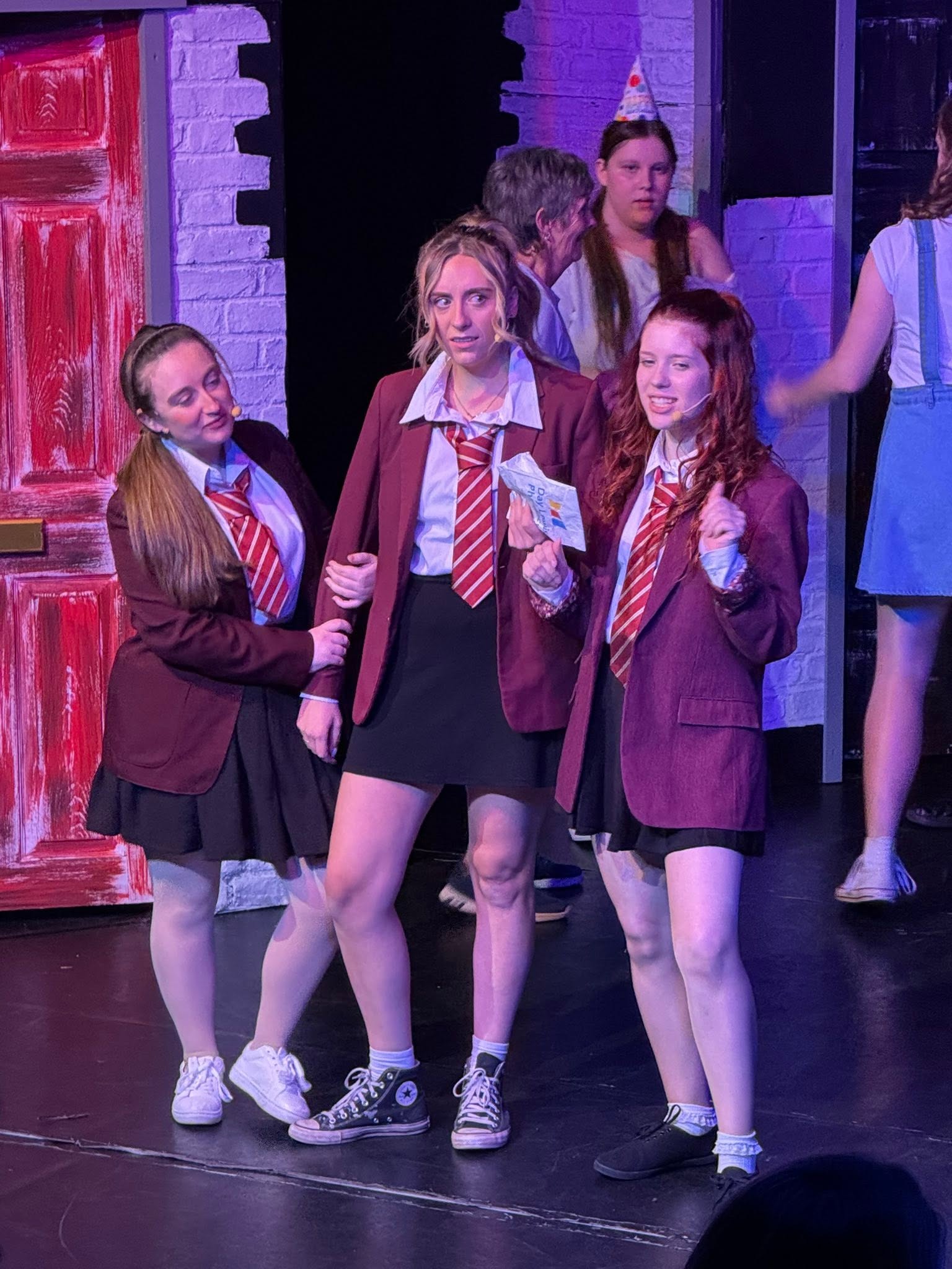 Performers in school uniforms during a stage scene