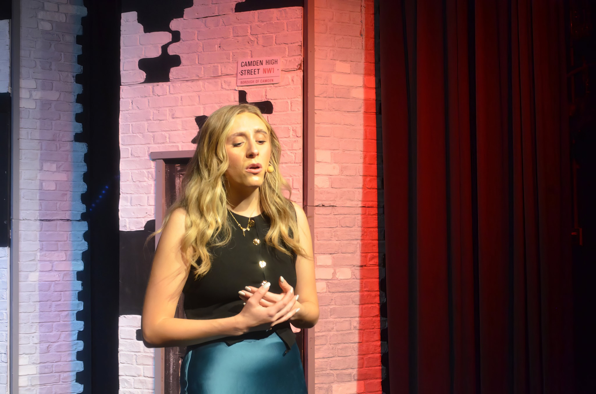 A singer performing beside a red stage curtain