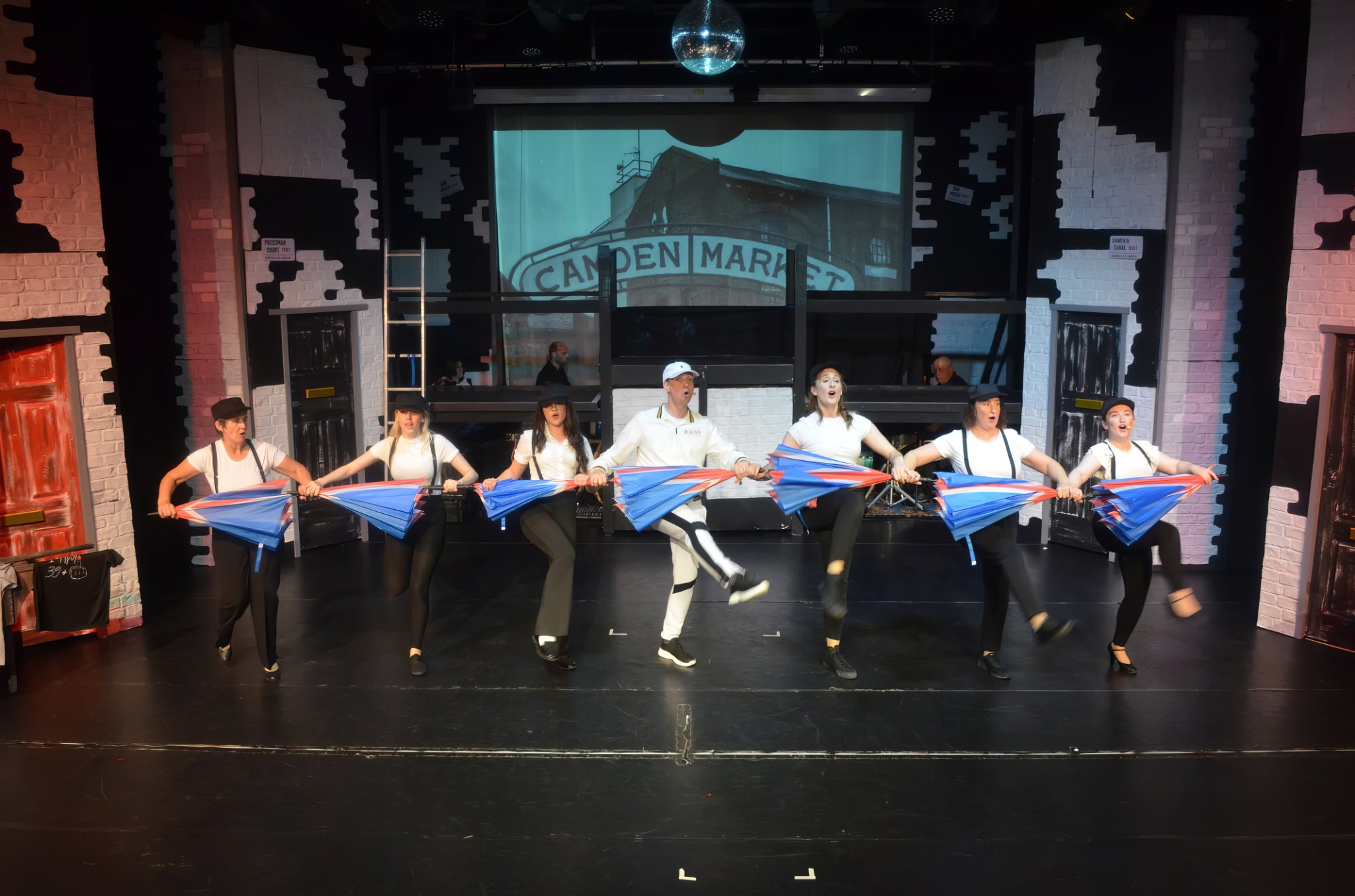 The ensemble dancing with umbrellas on stage