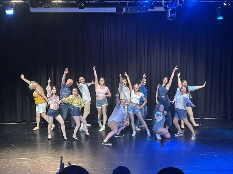 Performers rehearsing a dance with their arms raised