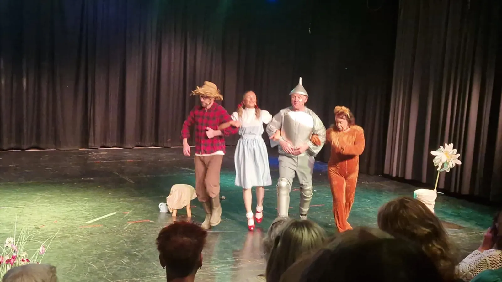 Four costumed performers on a stage with a green floor