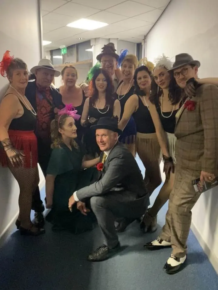 Company members posing together backstage
