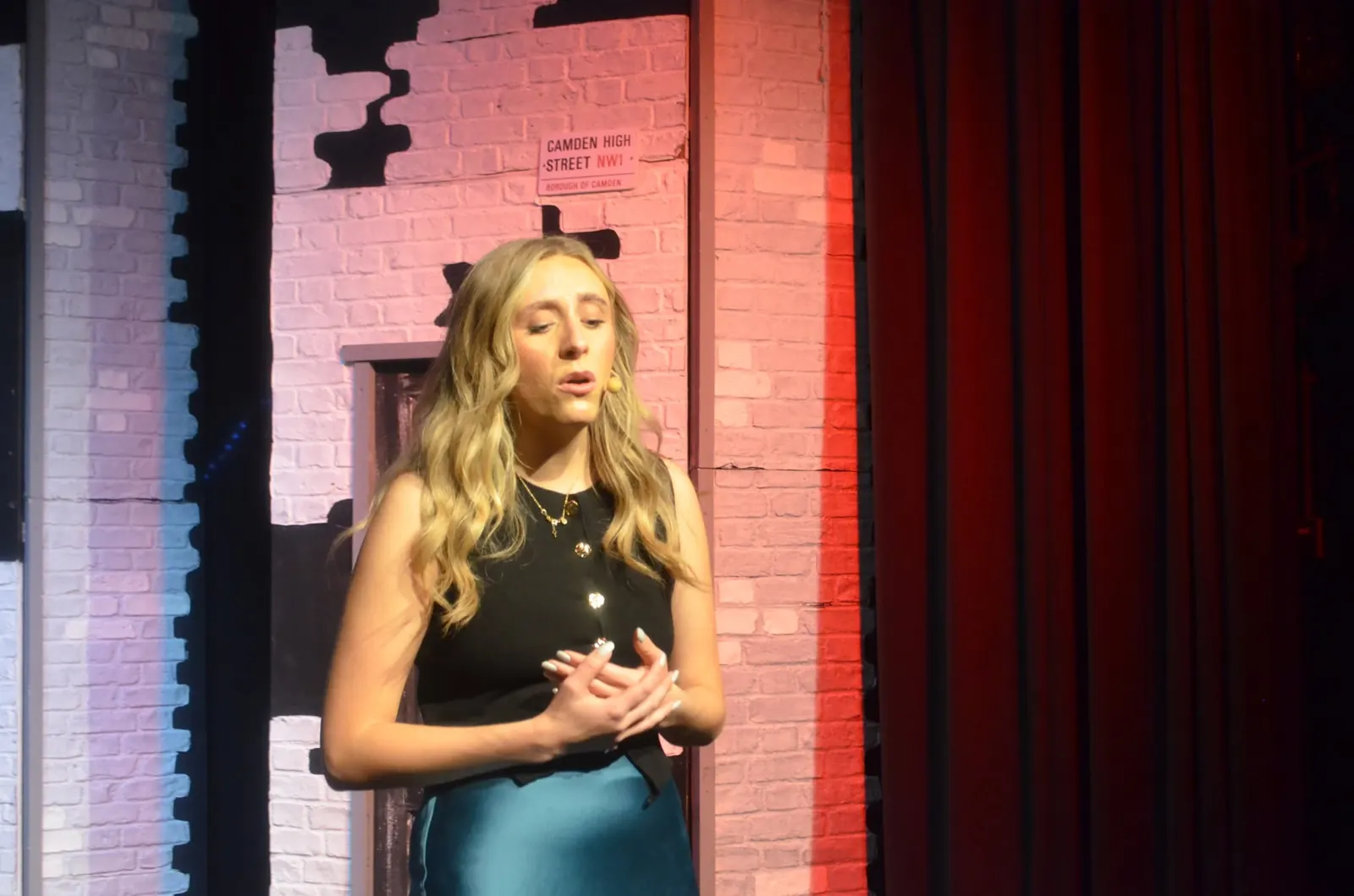 A performer singing beside a red curtain