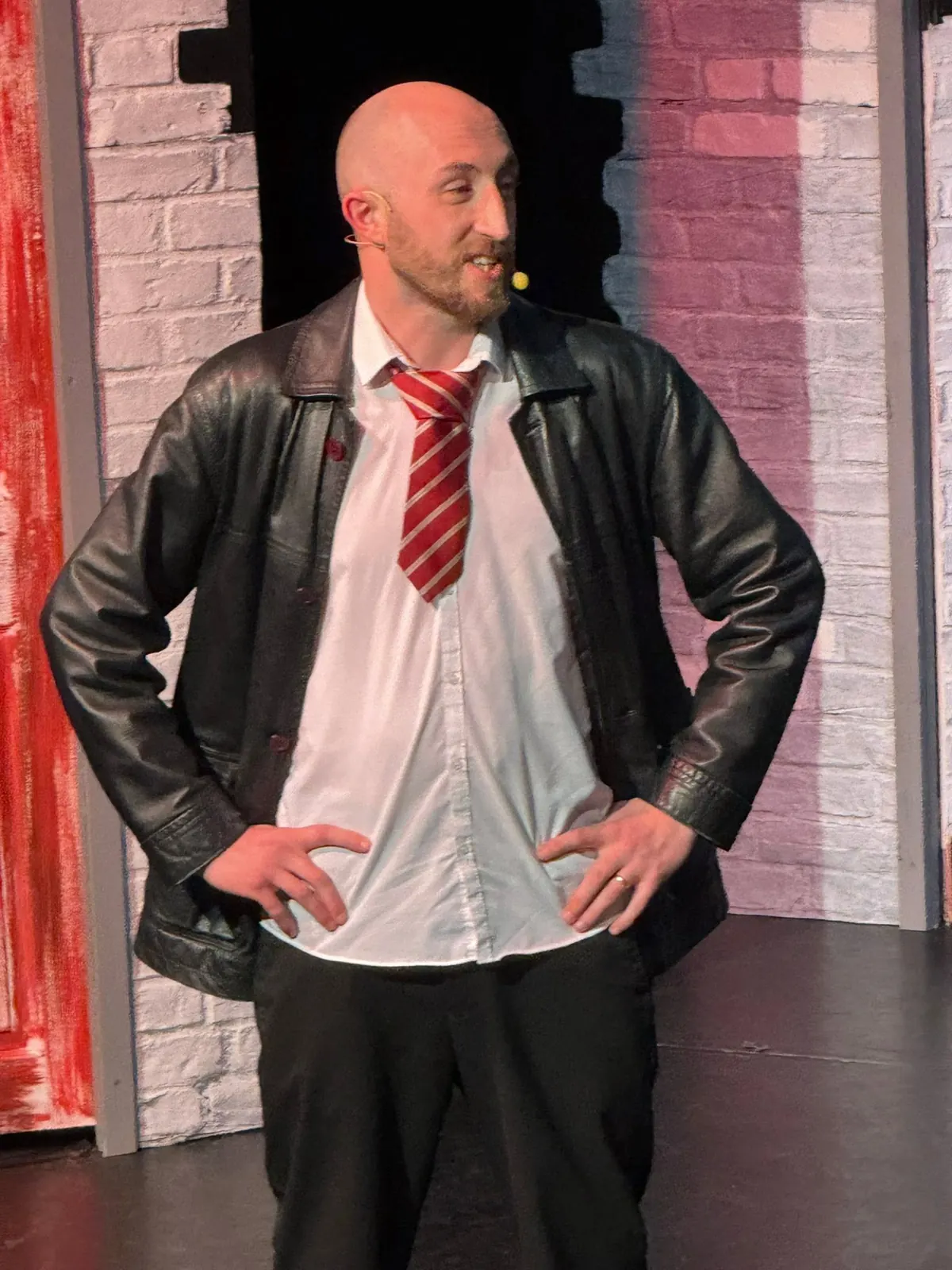 A performer in a leather jacket and striped tie