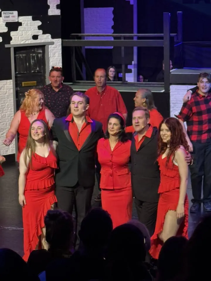 The company dressed in red and black on stage