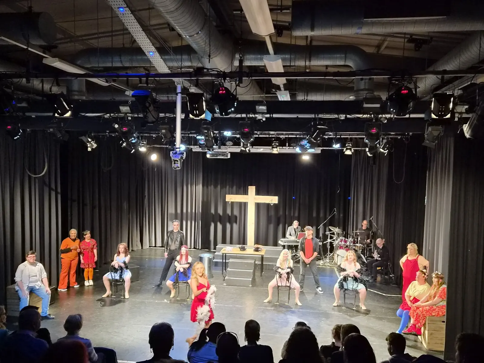 A company rehearsal on a stage with a large cross